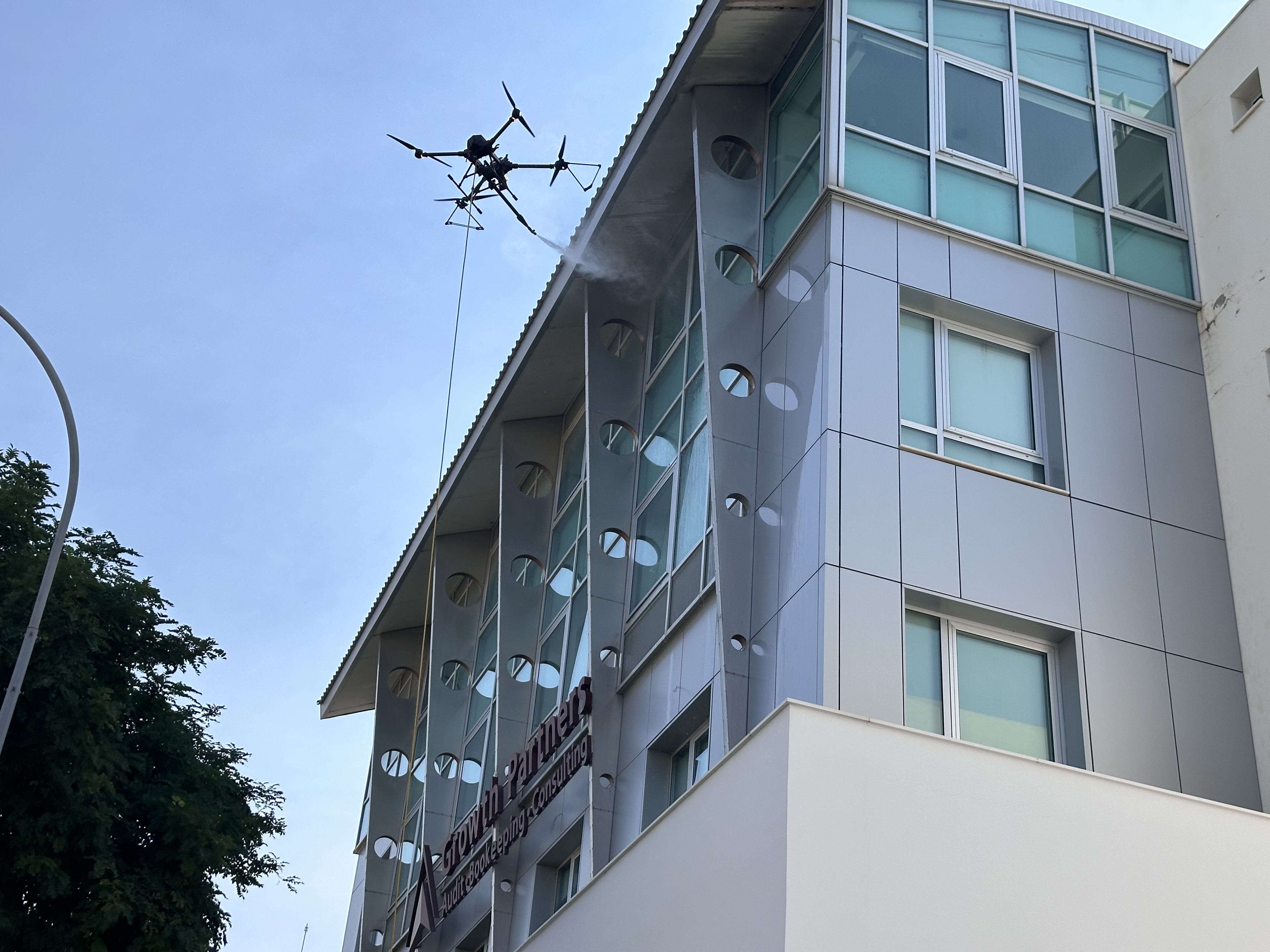 Drone spraying the Growth Partners building facade at height